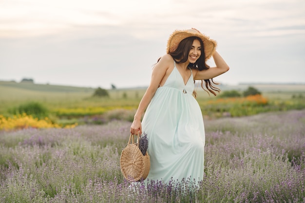 Mujer provenzal relajante en campo de lavanda. Dama con sombrero de paja. Chica con bolso.