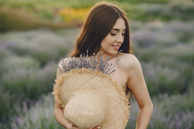 Mujer provenzal relajante en campo de lavanda. Dama con sombrero de paja.