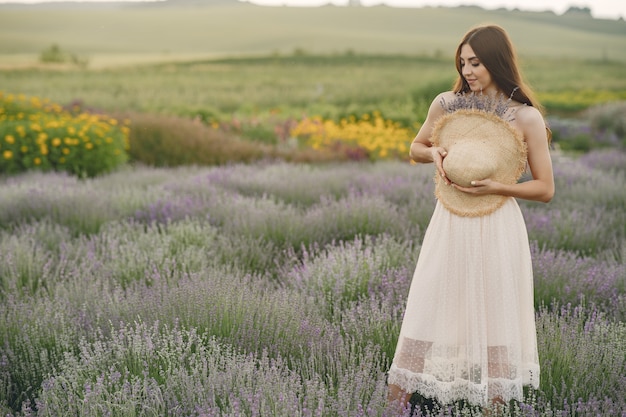 Mujer provenzal relajante en campo de lavanda. Dama con sombrero de paja.