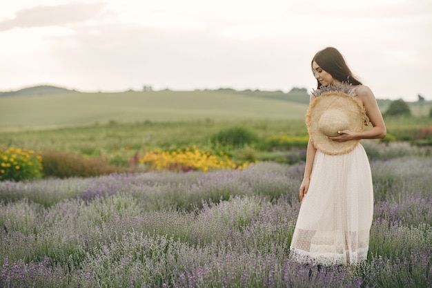 Mujer provenzal relajante en campo de lavanda. Dama con sombrero de paja.