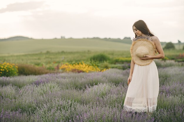 Mujer provenzal relajante en campo de lavanda. Dama con sombrero de paja.