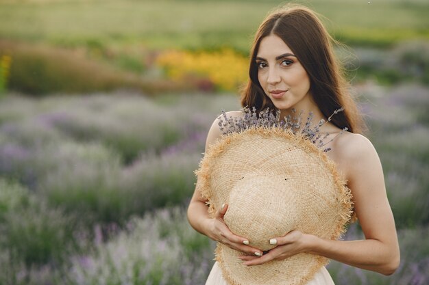 Mujer provenzal relajante en campo de lavanda. Dama con sombrero de paja.