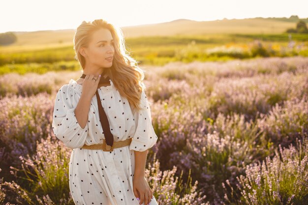 Mujer provenzal relajante en campo de lavanda. Dama con un vestido blanco. Chica con sombrero de paja.