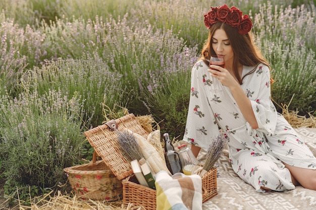 Mujer provenzal relajante en campo de lavanda. Señora en un picnic. Mujer en una corona de flores.