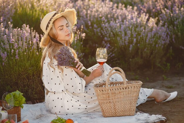 Mujer provenzal relajante en campo de lavanda. Señora en un picnic. Mujer con sombrero de paja.