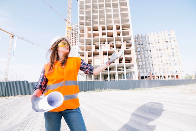 Mujer con proyecto gesticular en el sitio de construcción