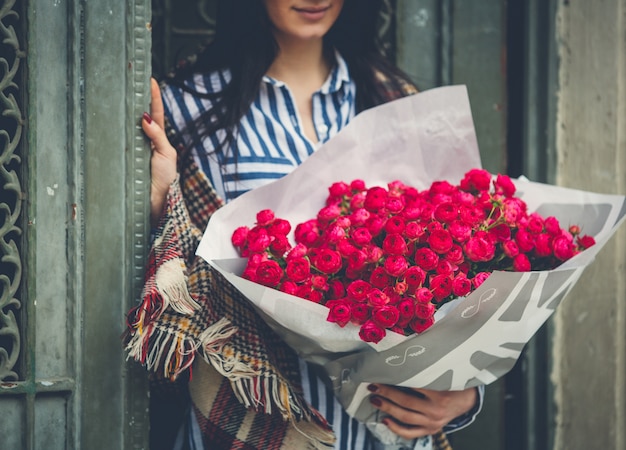 Mujer en la puerta con un gran ramo de flores rosadas