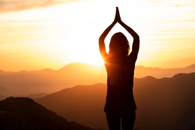 Mujer en la puesta de sol haciendo yoga