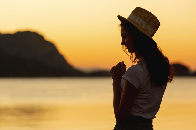 Mujer y puesta de sol en la orilla de un lago