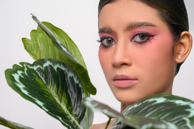 Foto gratuita mujer se puso maquillaje rosa y decorado con hojas aisladas en blanco