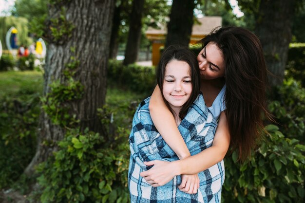 Mujer que abraza a la muchacha envuelta en cuadros a cuadros