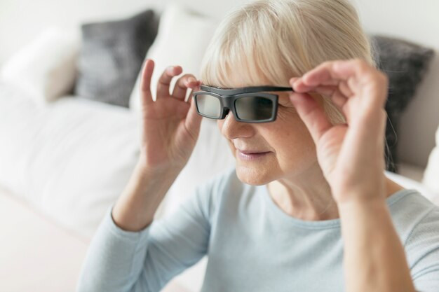 Mujer que ajusta gafas 3D mientras mira película