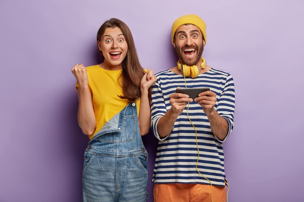 Mujer que anima feliz se regocija, un hombre sostiene el smartphone horizontalmente