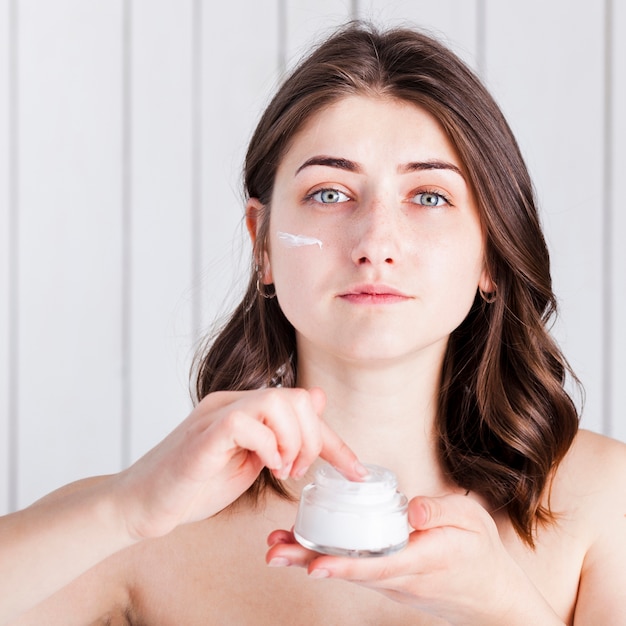 Mujer que aplica la crema en la cara