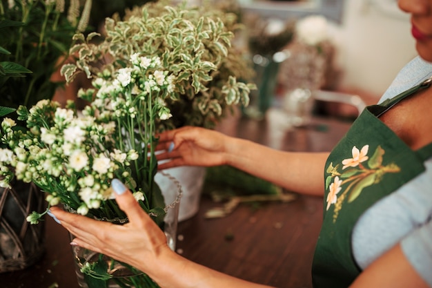 Mujer que arregla el manojo de flores en florero