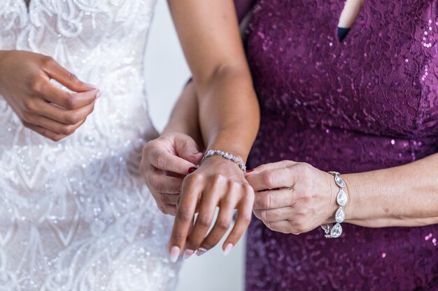 Mujer que ayuda a poner la pulsera en la muñeca de la novia