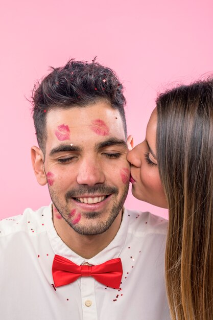 Mujer que besa al hombre con las marcas del beso del lápiz labial en mejilla