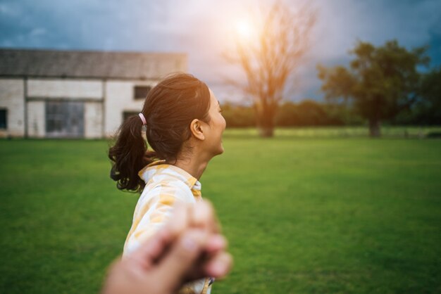 Mujer que camina en las vacaciones felices románticas que llevan a cabo la mano del novio que la sigue