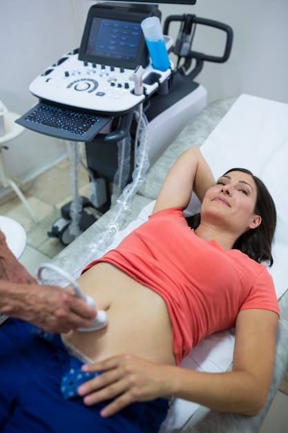 Mujer que consigue ultrasonido de un abdomen del médico