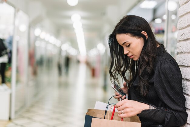 Mujer que controla bolsos de compras en tienda