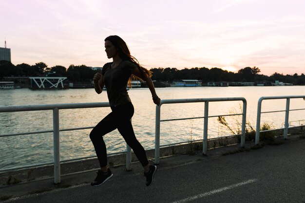 Mujer que corre en la calle al atardecer