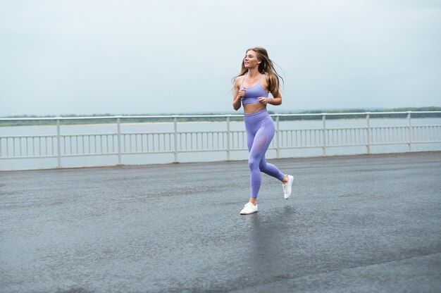 Mujer que corre a lo largo del lago tiro largo