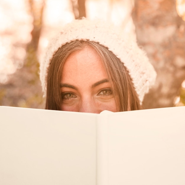 Mujer que cubre la cara con el libro en el bosque