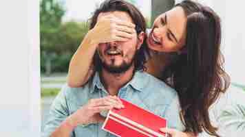 Foto gratuita mujer que cubre los ojos del hombre con caja de regalo