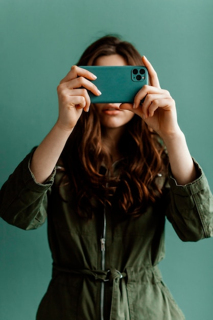 Foto gratuita mujer que cubre su rostro con un teléfono inteligente