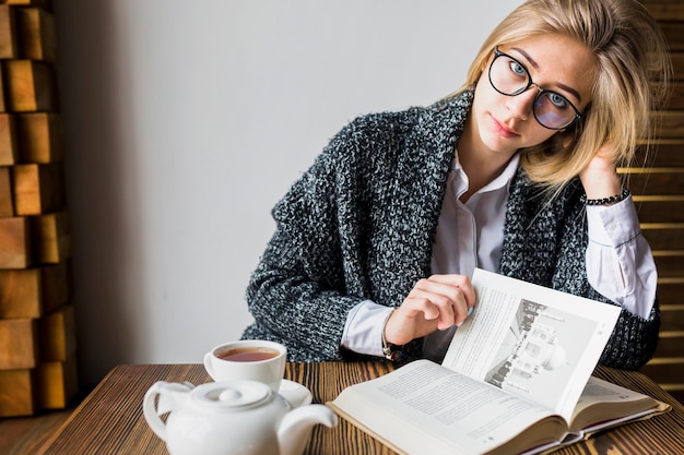 Mujer que da vuelta a las páginas del libro y que mira la cámara