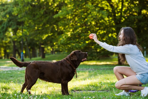 Mujer que se divierte con su perro en el jardín