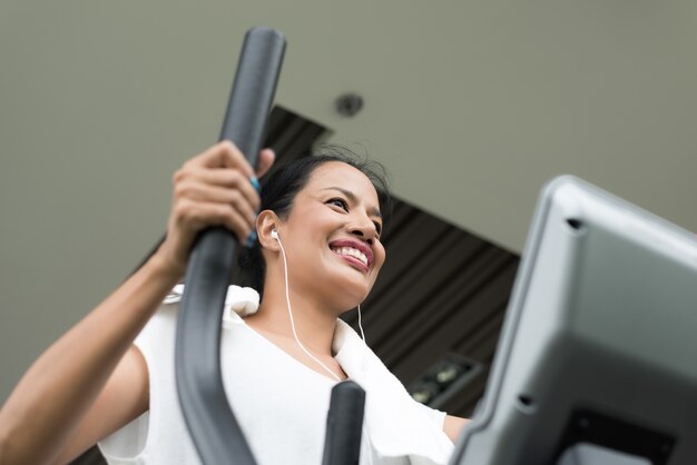 Mujer que ejercita y que se resuelve en gimnasio de la aptitud