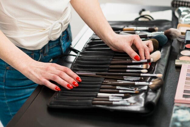 Mujer que elige el cepillo del maquillaje del sistema