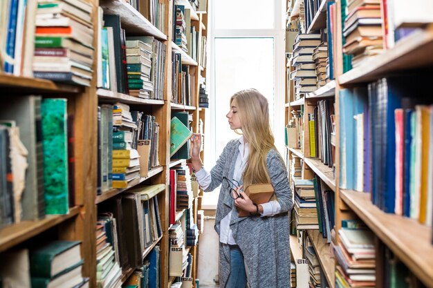 Mujer que elige el libro del estante