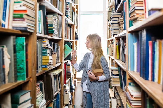 Mujer que elige el libro del estante