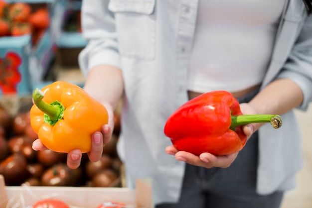 Mujer que elige el pimiento en la tienda de comestibles