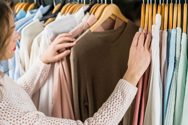 Mujer que elige el vestido durante compras en la ropa de la ropa