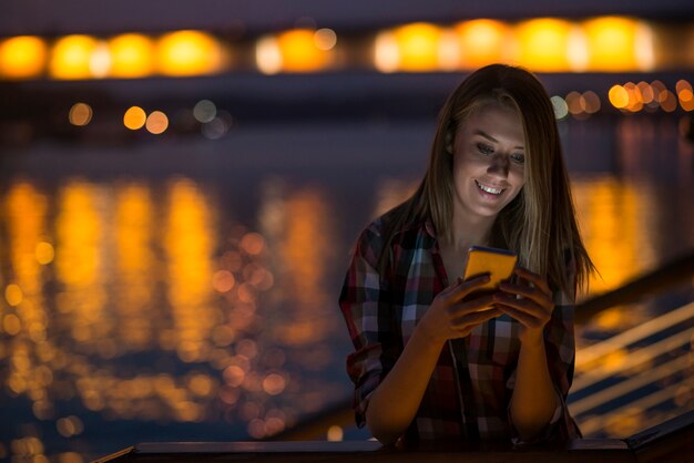 Mujer que envía el mensaje de texto en el teléfono. Retrato de una hermosa gir