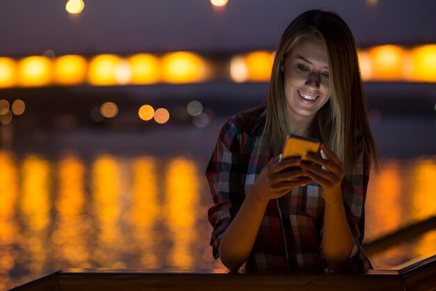 Mujer que envía el mensaje de texto en el teléfono. Retrato de una hermosa gir