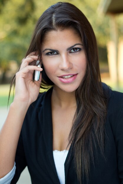 Mujer que habla el teléfono y mirando a la cámara