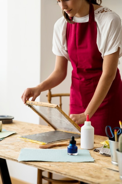 Mujer que hace el papel en el escritorio de madera en taller