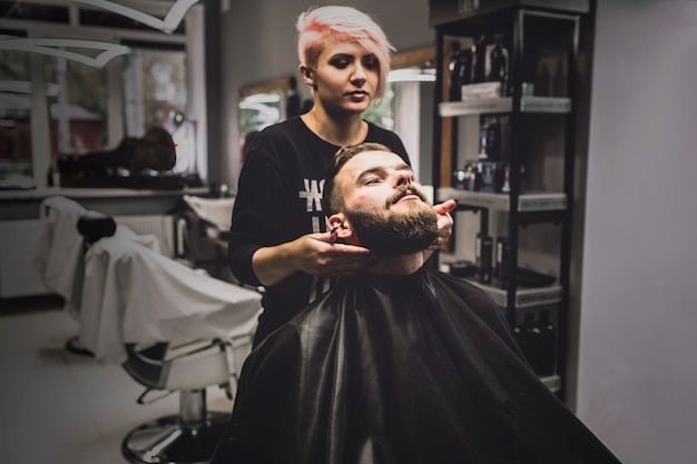 Foto gratuita mujer que hace el tratamiento para el cliente en barbería