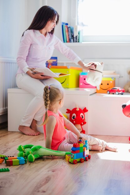 Mujer que juega con el niño en sala de juegos