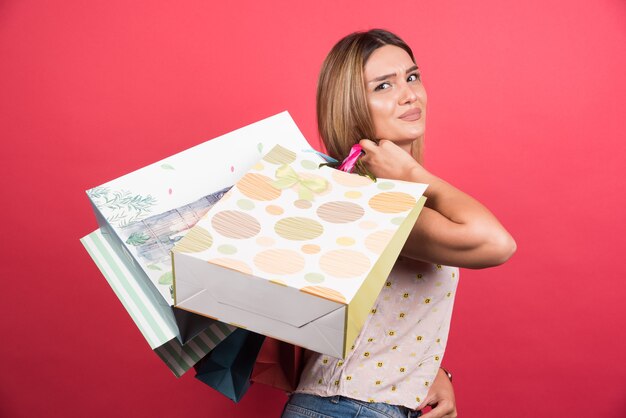 Mujer que lleva bolsas de la compra con expresión neutra.