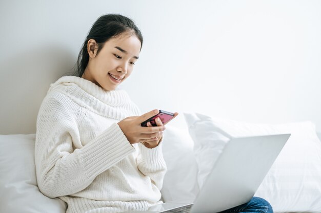 Una mujer que llevaba una camisa blanca jugando un teléfono inteligente