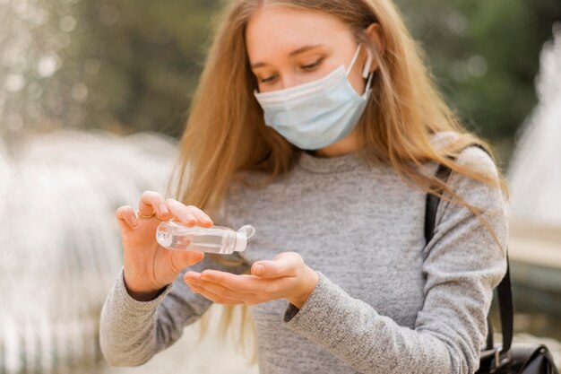 Mujer que llevaba una máscara médica mientras está sentado junto a una fuente