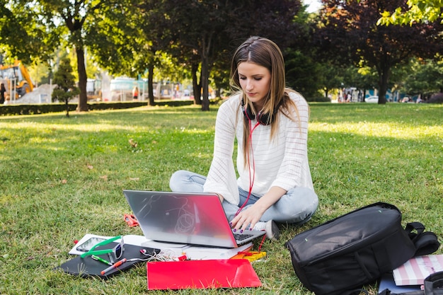 Foto gratuita mujer que mecanografía en la computadora portátil mientras que estudia