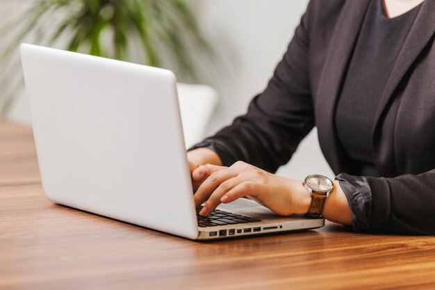 Mujer que mecanografía en la computadora portátil en oficina