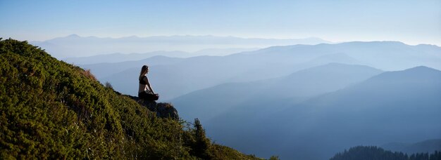 La mujer que medita se relaja en las montañas