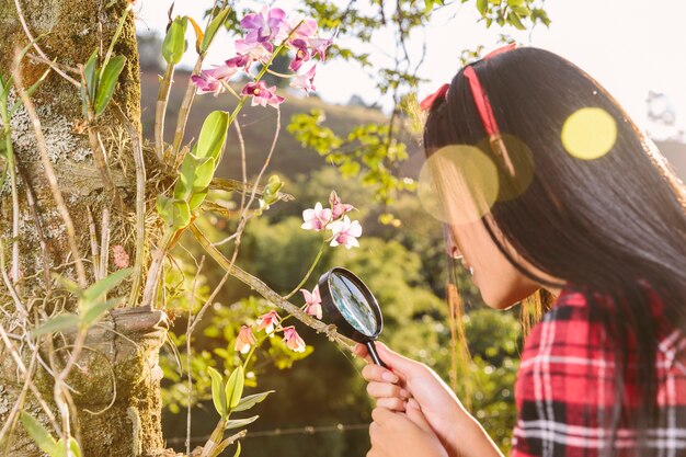 Mujer que mira la flor a través de la lupa